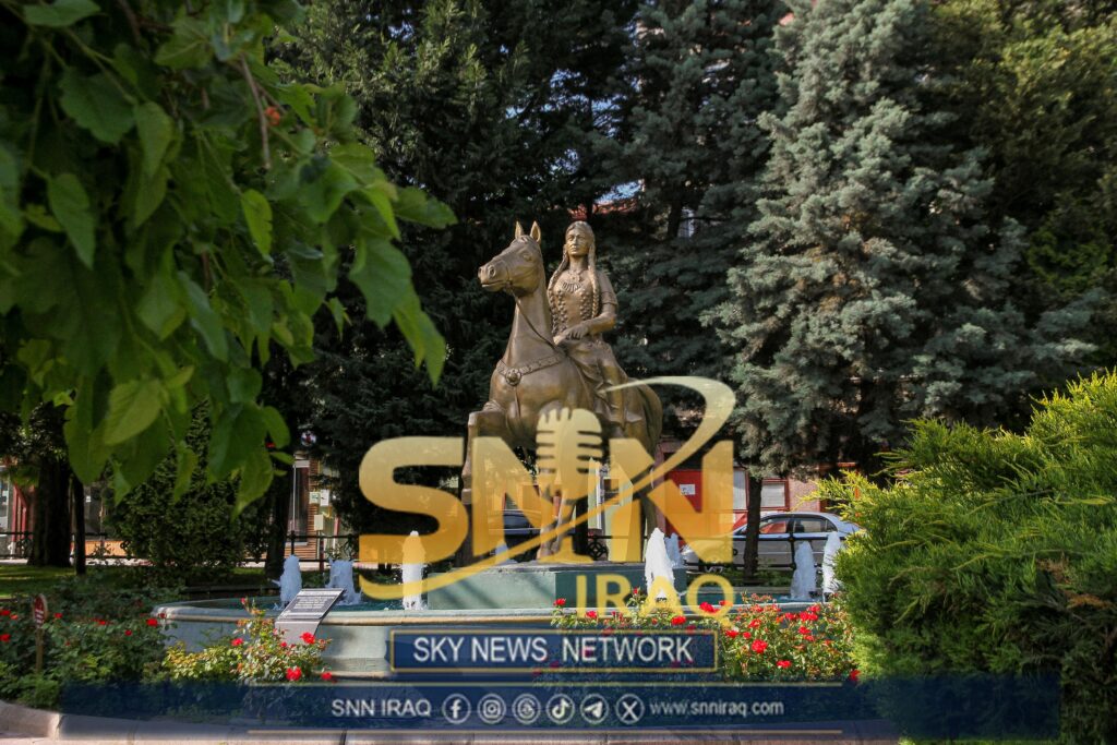 Equestrian statue in a vibrant park setting with fountains and lush greenery.