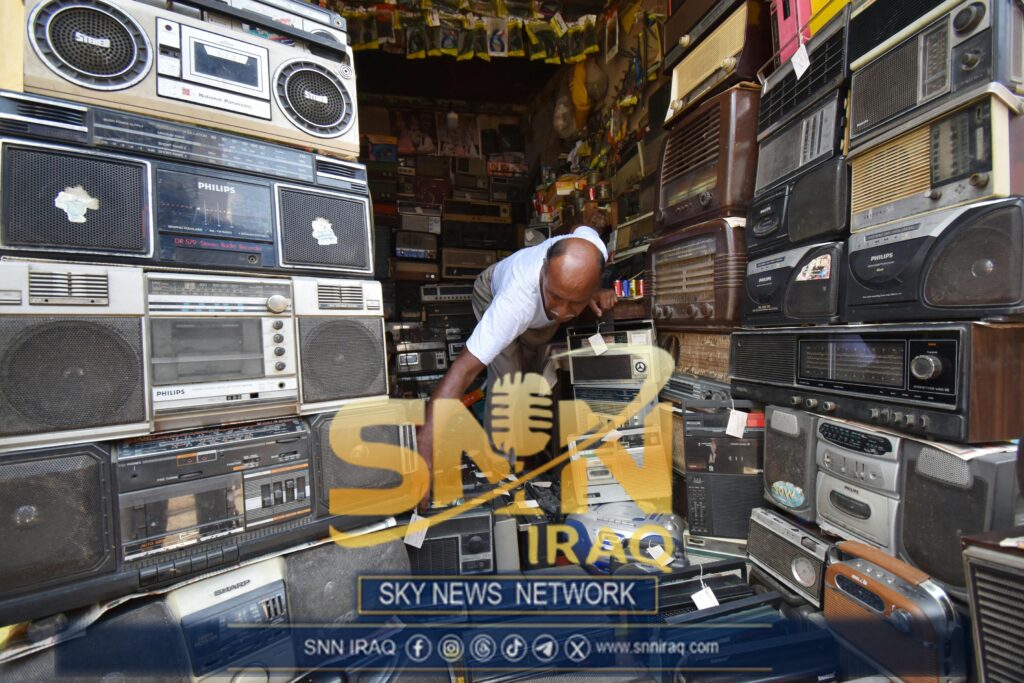 Man in Kolkata shop filled with vintage radios and electronics. Nostalgic atmosphere.