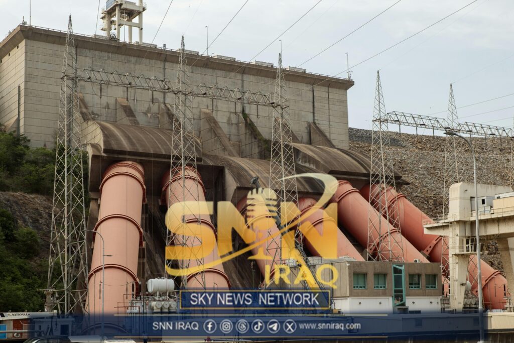 Industrial view of a massive hydroelectric dam with large pipes and power lines.