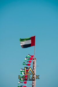 The national flag of the United Arab Emirates waving majestically against a clear blue sky.