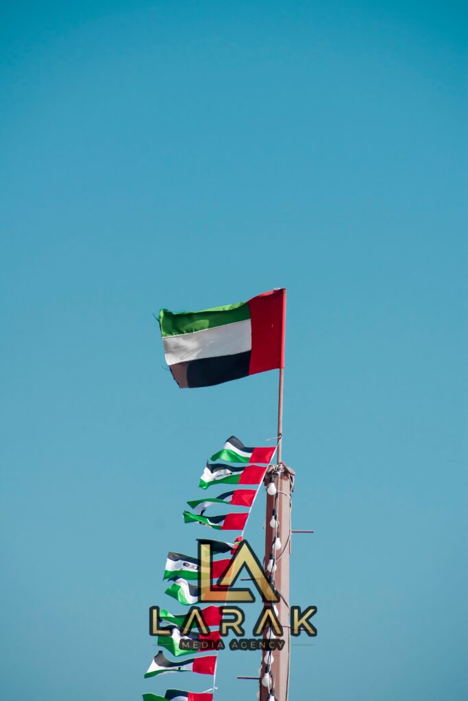 The national flag of the United Arab Emirates waving majestically against a clear blue sky.