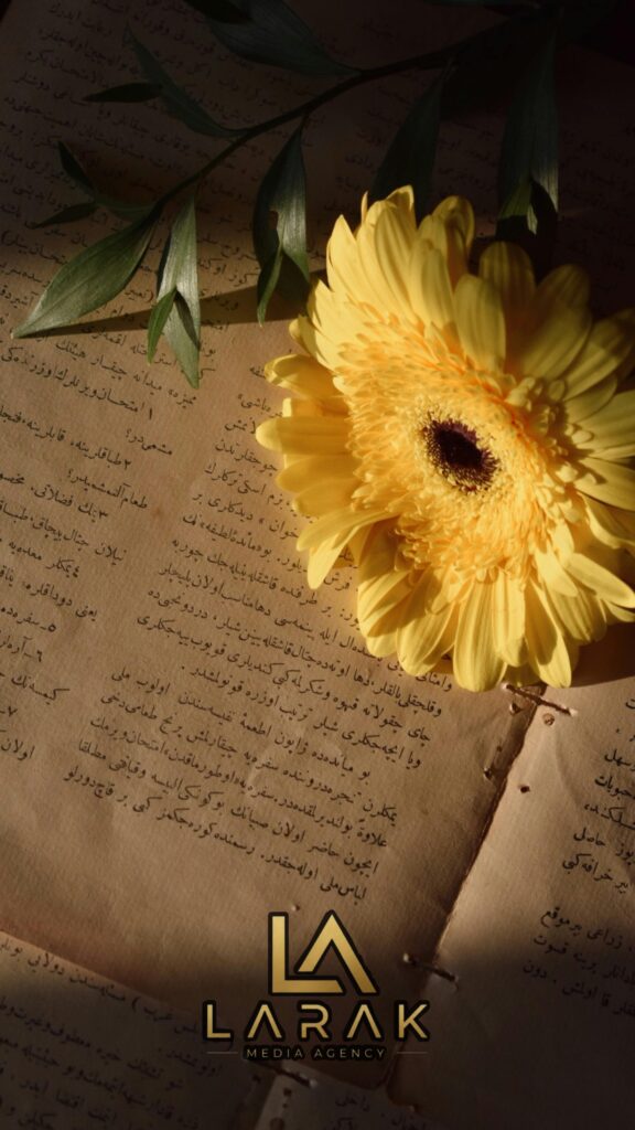 Yellow gerbera flower on vintage text pages with leaves, soft light
