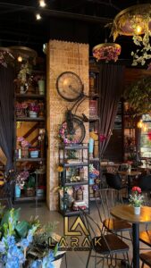 Charming cafe interior with floral decor, hanging plants, and bicycle wall art, creating a cozy atmosphere.
